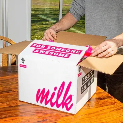 person opening a Milk Bar box that states