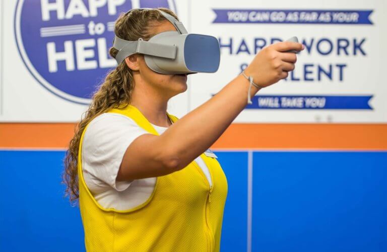 Woman wearing yellow vest, pointing at something off-camera.