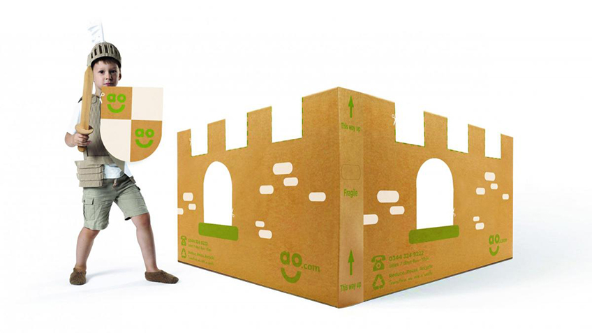 A cardboard castle set up on the floor, with a person standing in front of it.
