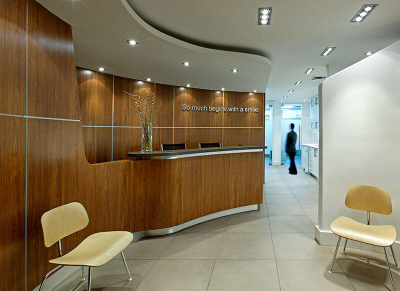 An interior view of a modern office space featuring a reception area with a desk, chair, and a sign that reads 