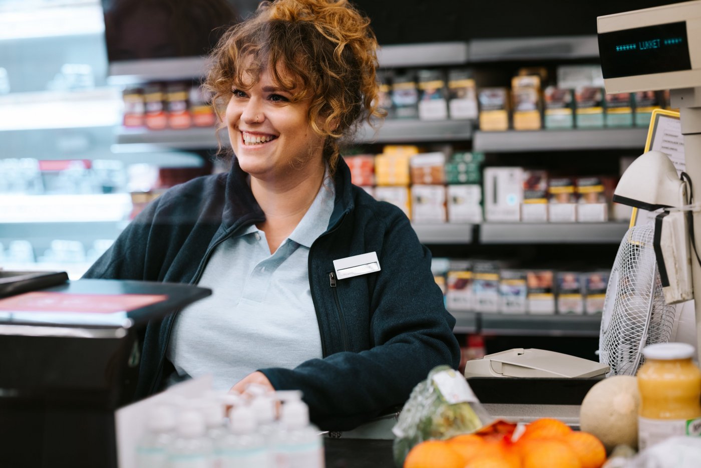 Woman standing behind counter at store, smiling.