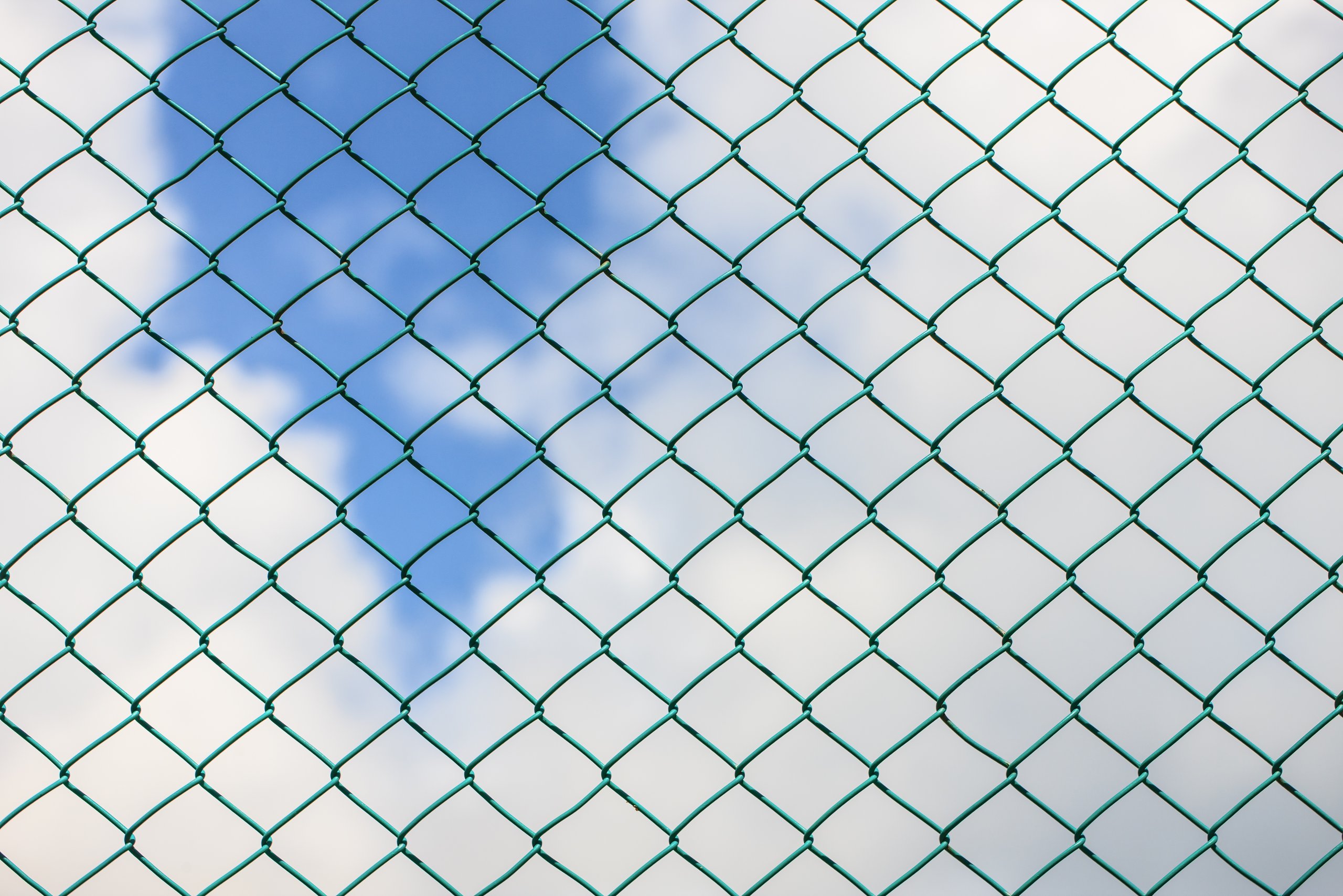 A chain link fence with blue sky background.