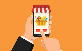 A person holding a smartphone displaying an app with a shopping cart icon, suggesting online grocery shopping