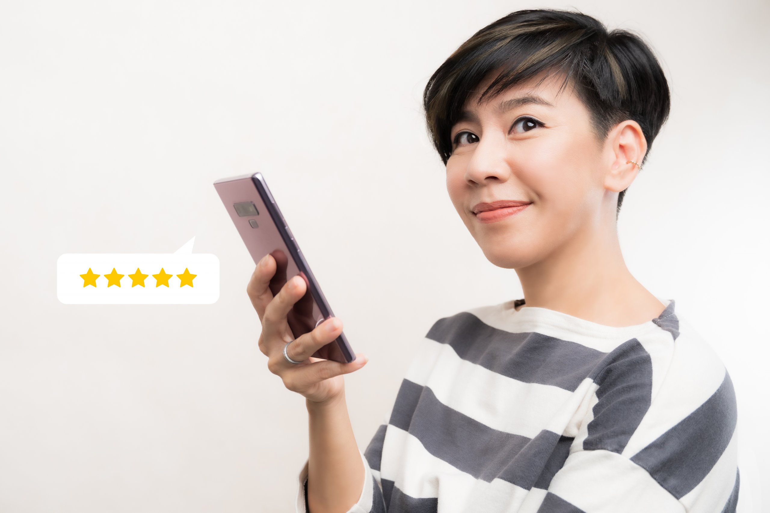 Woman holding a phone, smiling at the camera.