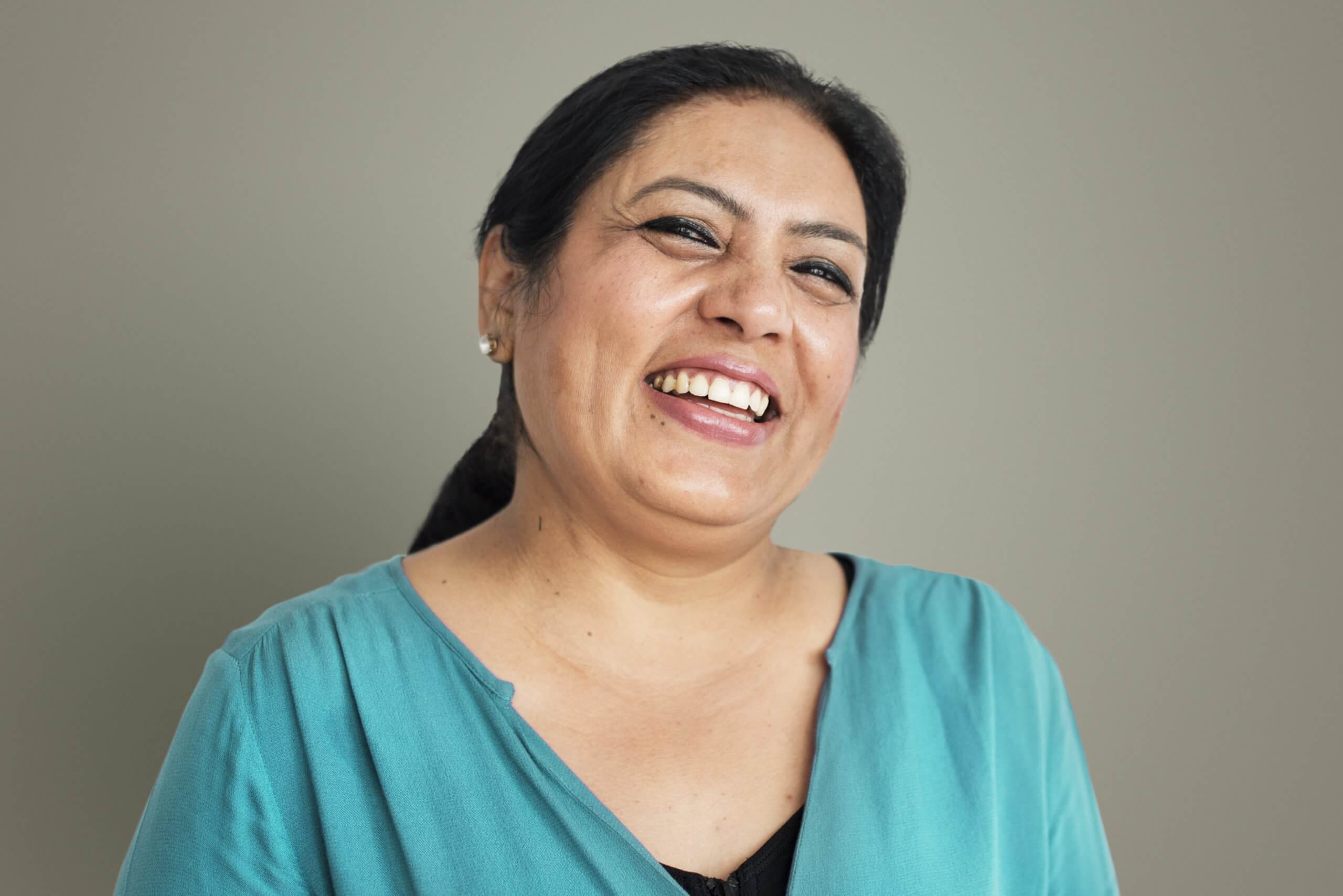A woman smiling at the camera, wearing a blue top