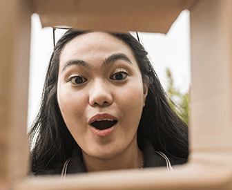 Woman making a silly face through a cardboard cutout.