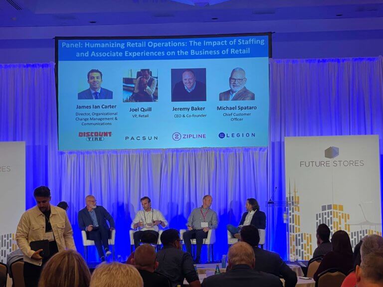 A panel discussion at a conference about the impact of human resources on retail operations, featuring three men in suits sitting behind a podium.