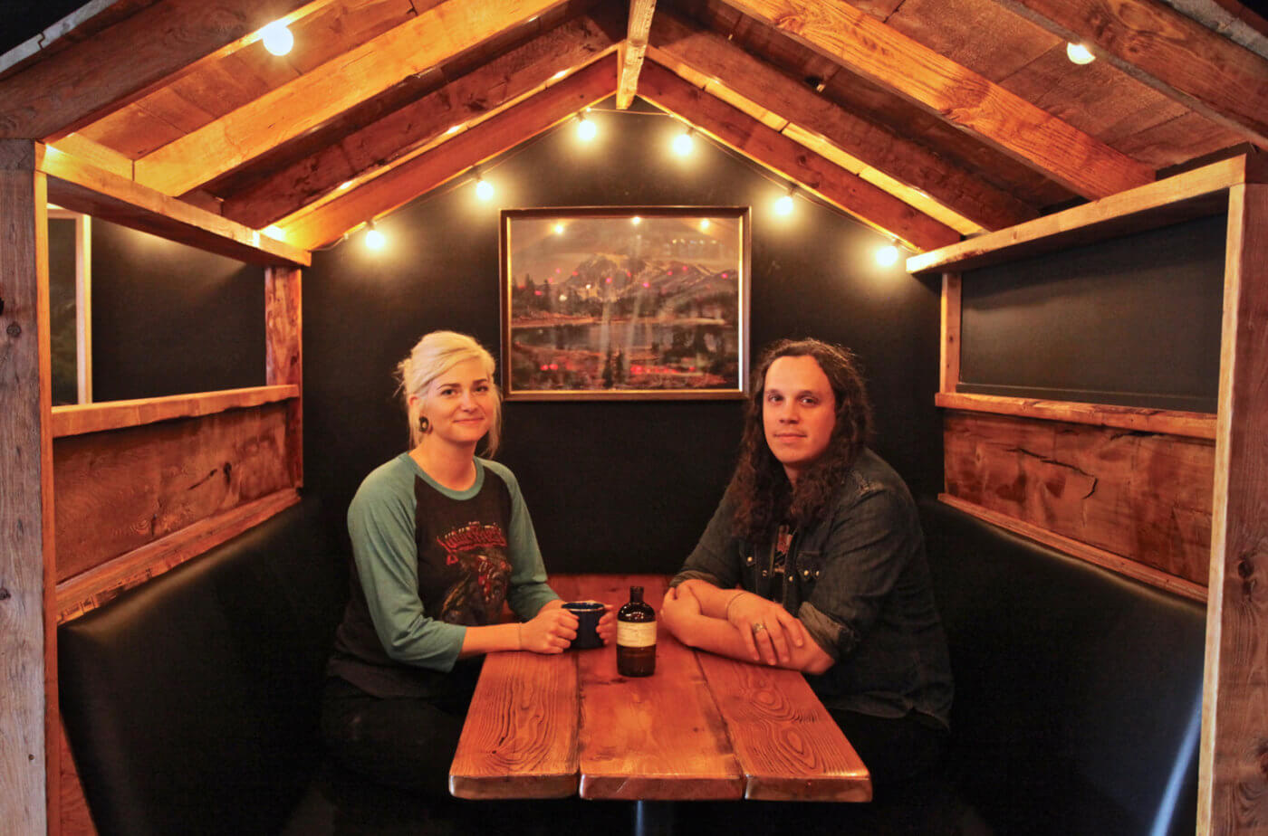 Two people sitting at a table inside a rustic wooden cabin-style restaurant.