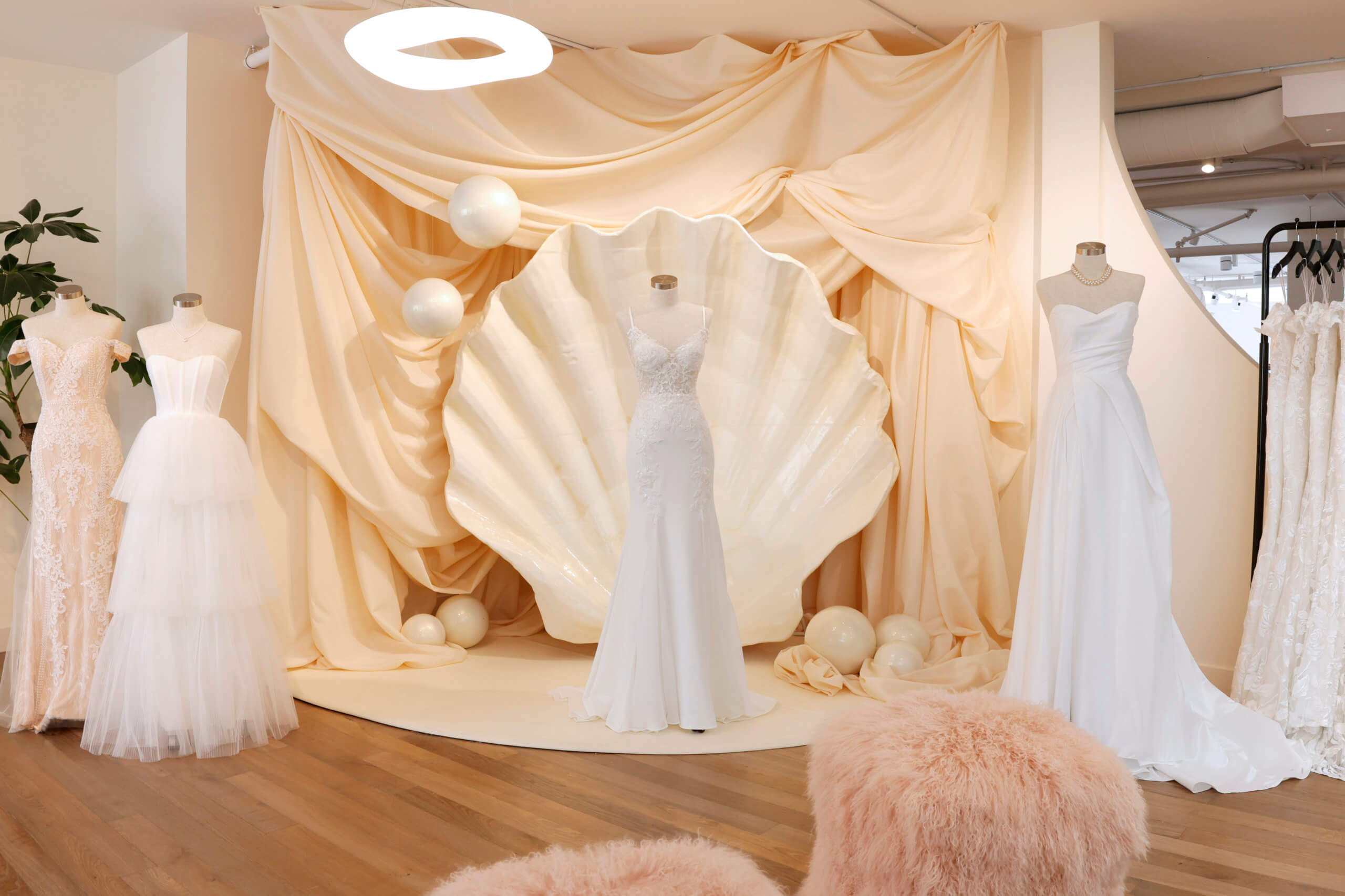 An image of a store displaying wedding dresses. The dresses are displayed on mannequins, and the store has a stage set up in the background.