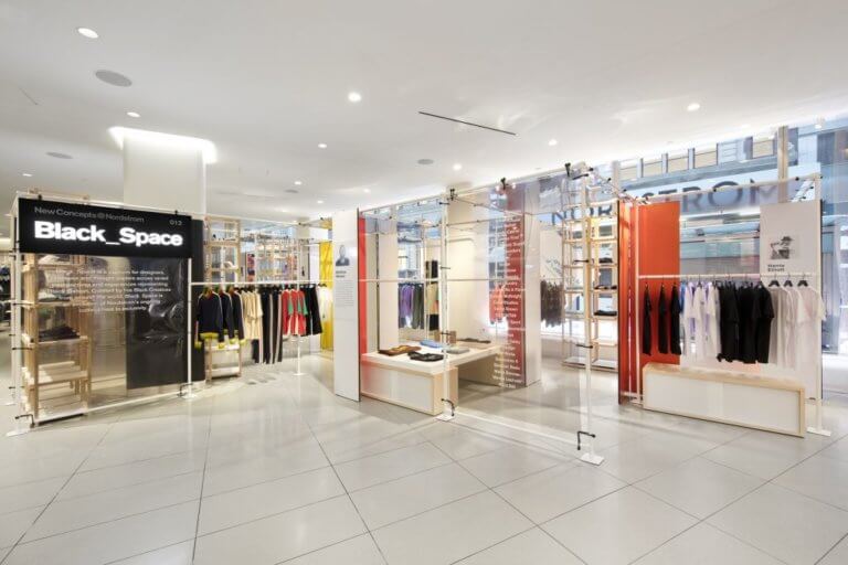 An interior view of a store, featuring a display of clothing items on mannequins, with various colors and styles visible. The store has a modern…