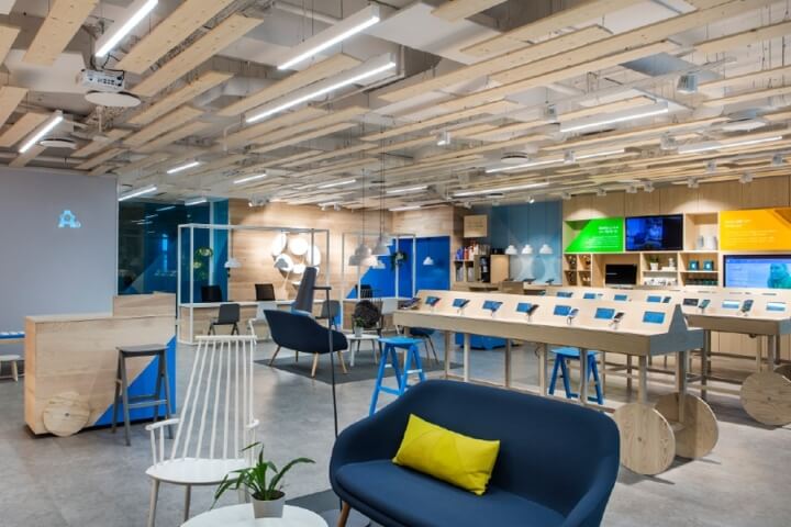 A modern office space with blue walls, white ceiling, and various furniture pieces.