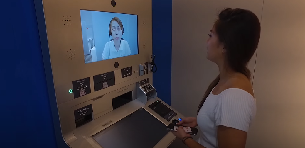 Woman standing in front of an ATM machine, interacting with it.