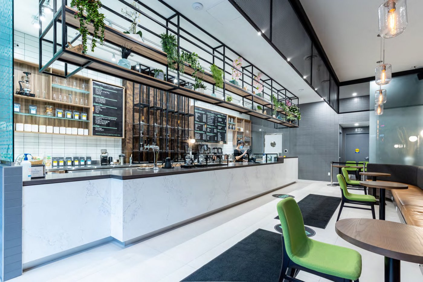 A modern cafe interior with a counter, chairs, and plants.