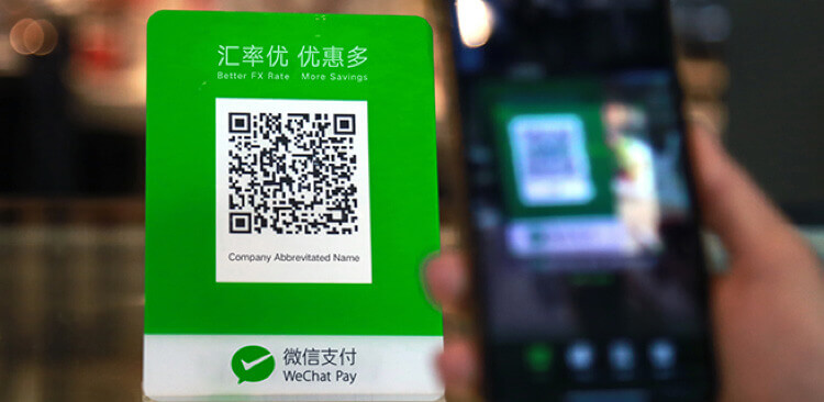 A cell phone displaying a green qr code on the screen, next to a white sign with a green logo and chinese characters.