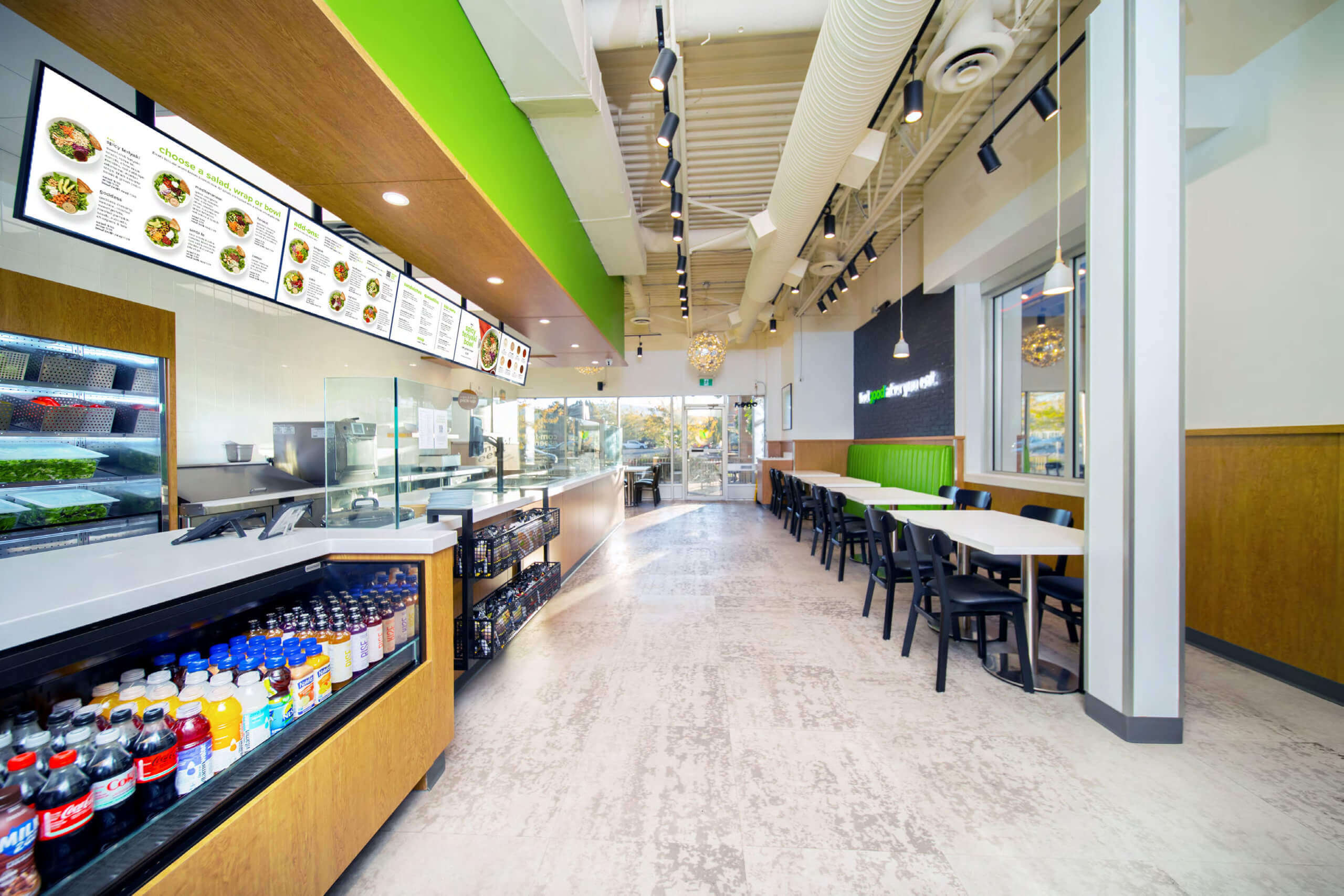 A modern restaurant interior with a green wall, white countertops, and various food items on display.