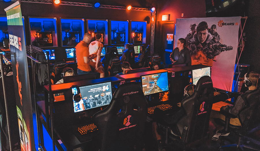 A group of people gathered around gaming computers, playing video games in a room.