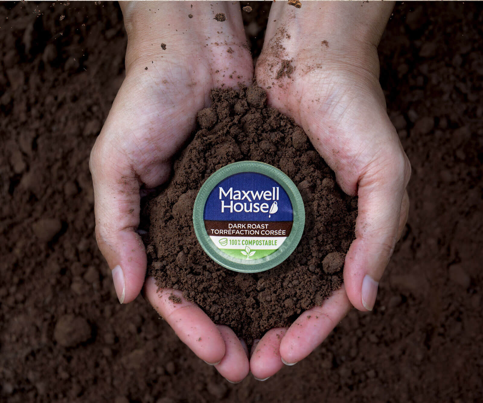 A hand holding a cup of coffee soil, with the label