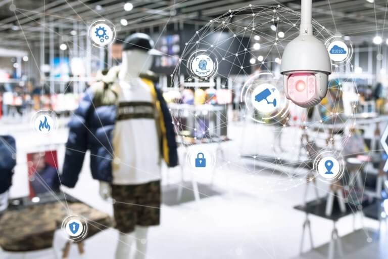 An image of a store interior, featuring mannequins displaying clothing, various electronic devices, and security cameras.