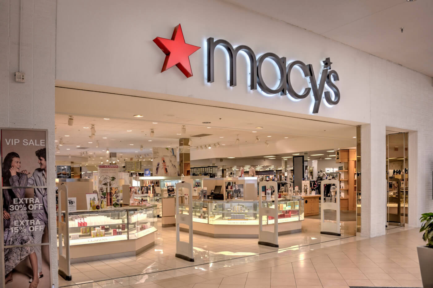 Macy's department store entrance with signage, display windows, and interior lighting.