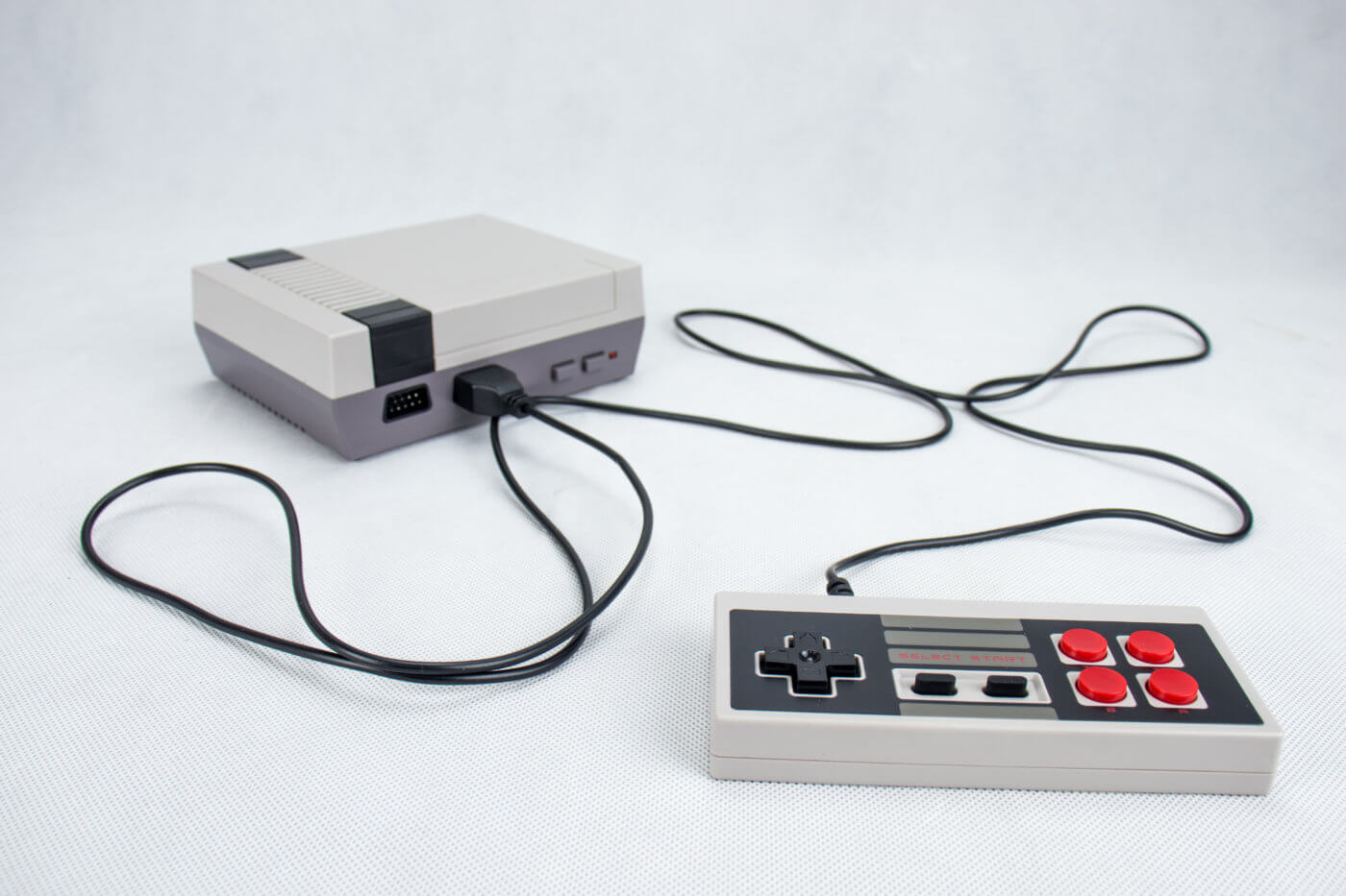 A Nintendo Entertainment System console, complete with its original controllers and power supply, set against a white background.