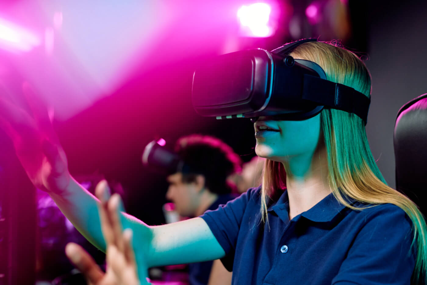 A woman wearing a VR headset, standing in front of a colorful background.