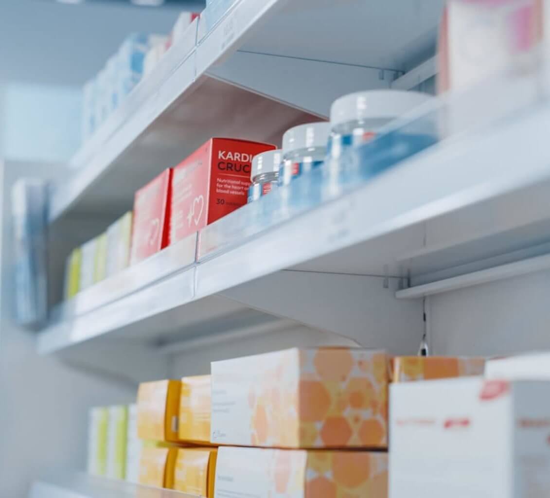 A shelf stocked with various medications and boxes in a pharmacy.