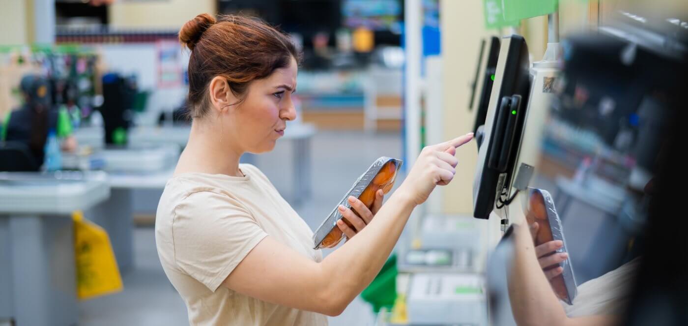 Woman standing at a cash register, holding a credit card.