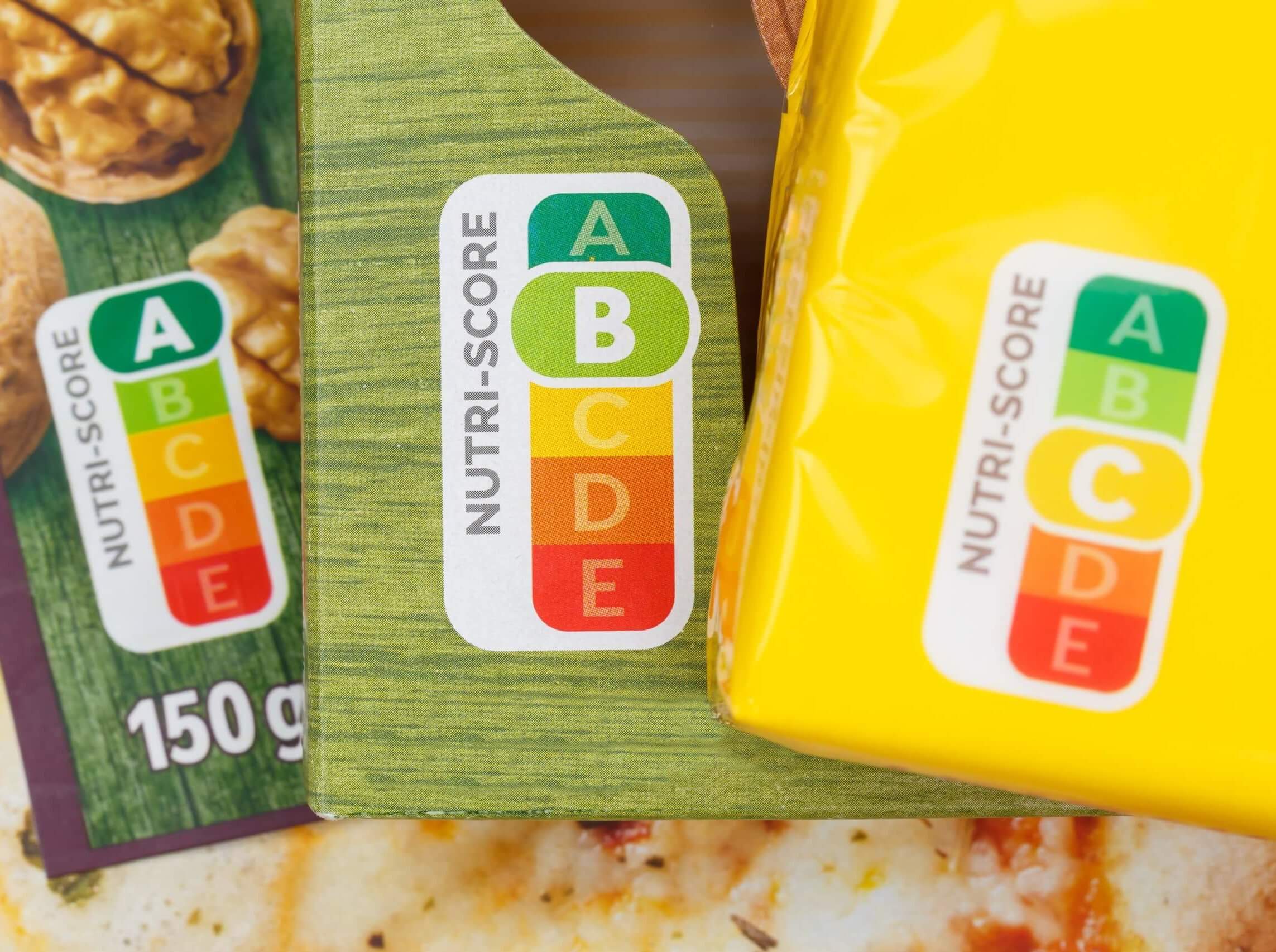 Two packets of nutri score food, one yellow and one green, on a table.