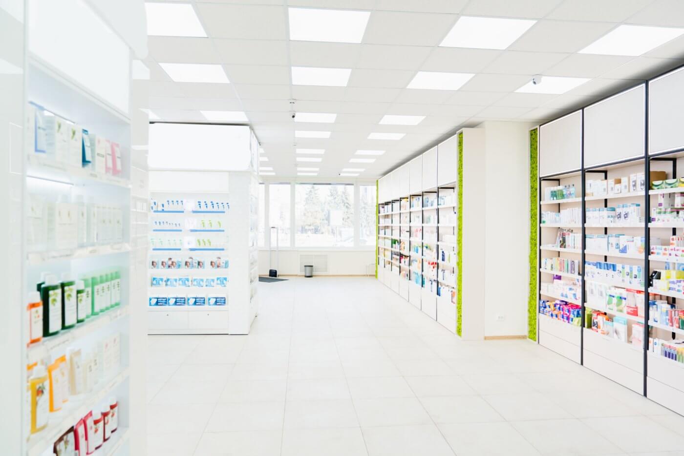 A well-lit pharmacy store with shelves stocked with various products, a large display case in the center, and a clean, organized appearance.