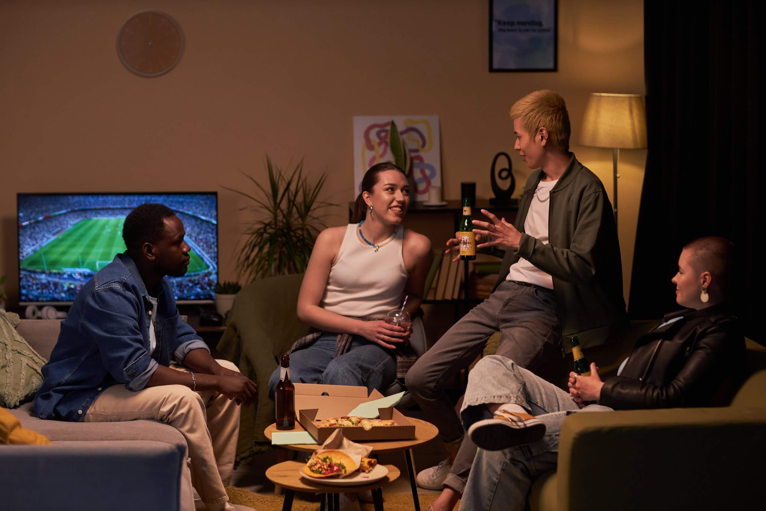 A group of people sitting on a couch, engaged in conversation, in a living room setting.