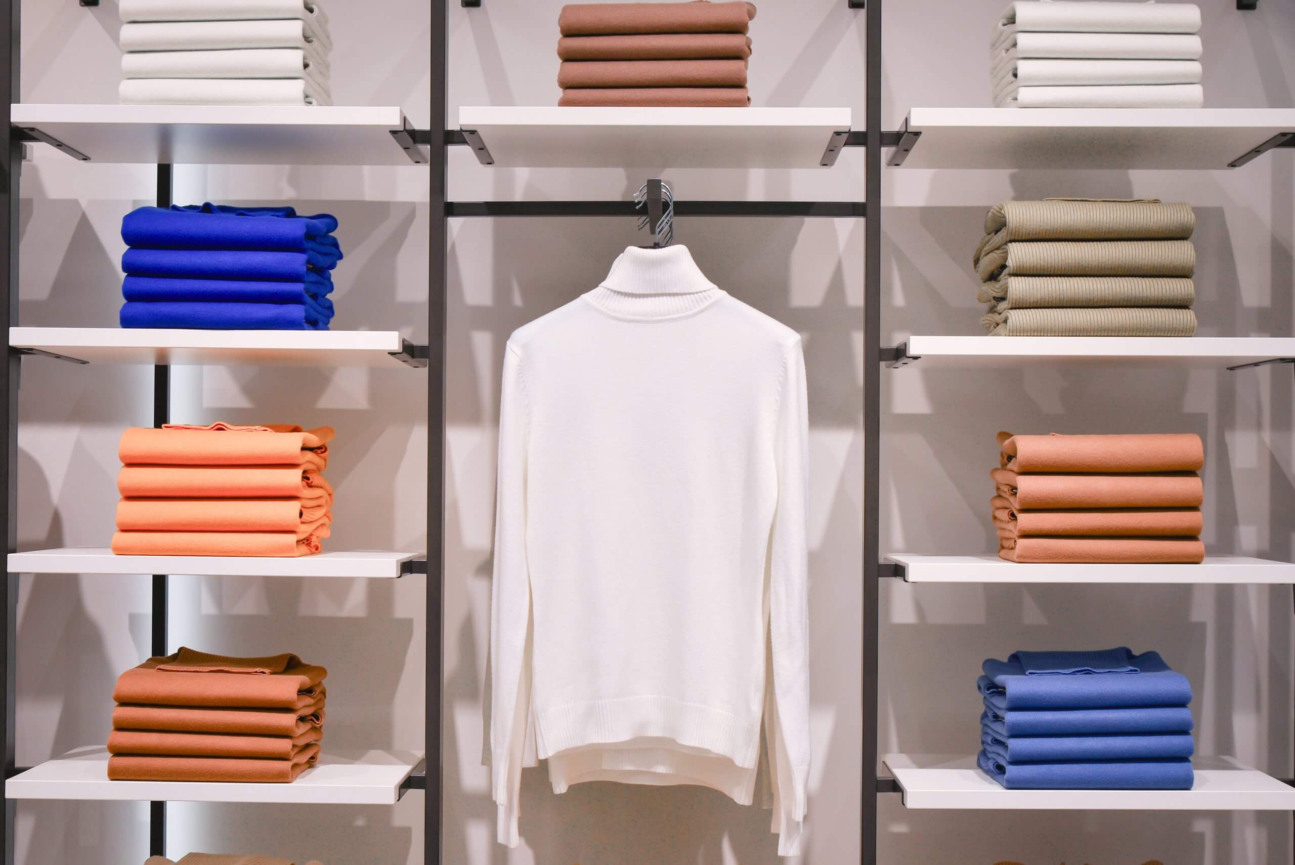 A display shelf filled with various colors of sweaters.