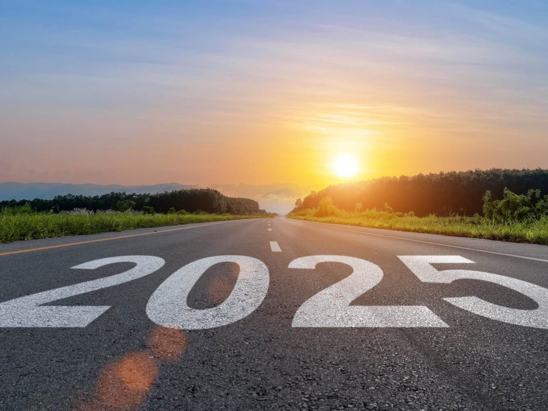 A sunset over a road with the year "2025" prominently displayed on it, suggesting a future time frame.