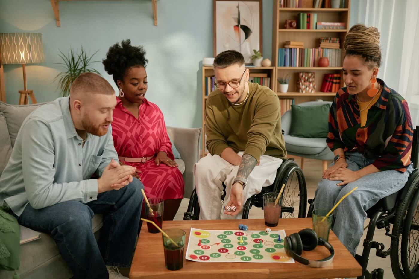 A group of four people sitting around a table playing a board game, with drinks in front of them.